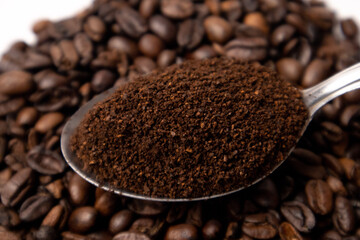 Detail of coffee on a metal spoon over coffee beans