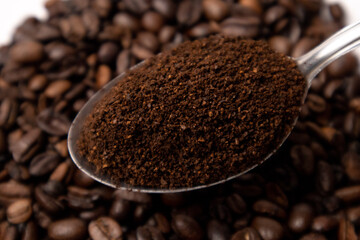 Detail of coffee on a metal spoon over coffee beans