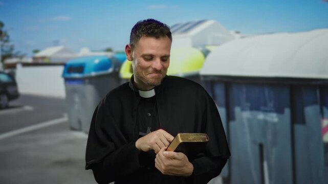 Priest laughing on urban street holding book in sunny day with colorful bins in background showing friendly humor
