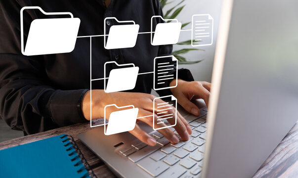 A woman is typing on a laptop with a white background and a diagram of folders on the screen. The folders are labeled with different names, and the woman is focused on her work