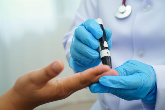 Asian woman self testing to check blood sugar level diabetes by digital lancet on finger at home.