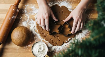 Hands cutting holiday shapes from raw gingerbread dough using cookie cutters on a flour-dusted wooden table.