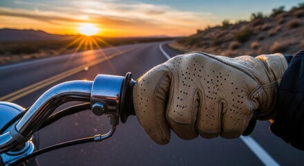 Motorcycle journey during sunset with a gloved hand gripping the handlebar tightly