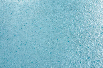 Raindrops fall on the blue sea water surface