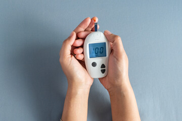 Woman's hands checking diabetes and hyperglycemia with digital blood sugar meter. Healthcare and medical concept	