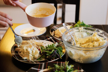 Woman pouring gravy over turkey for christmas dinner at home