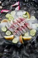 Arrange the glistening, white slices of fresh fish on a black round porcelain plate.