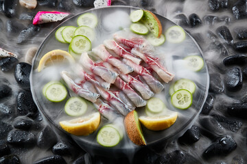 Arrange the glistening, white slices of fresh fish on a black round porcelain plate.