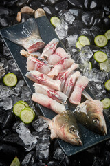 Arrange the glistening, white slices of fresh fish on a black round porcelain plate.