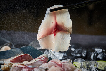 Arrange the glistening, white slices of fresh fish on a black round porcelain plate.