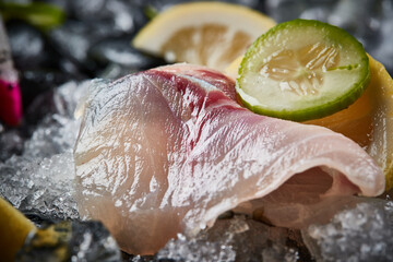 Arrange the glistening, white slices of fresh fish on a black round porcelain plate.