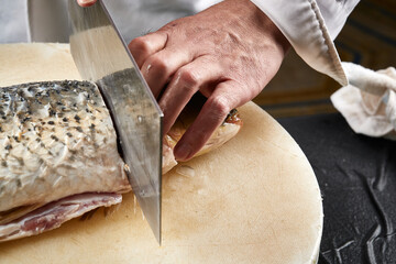 On a white cutting board, the chef demonstrates his exquisite knife skills in cutting and slicing sashimi and fresh fish.