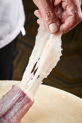 On a white cutting board, the chef demonstrates his exquisite knife skills in cutting and slicing sashimi and fresh fish.
