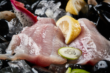 Arrange the glistening, white slices of fresh fish on a black round porcelain plate.