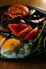 Grilled vegetables with fried eggs and herbs on breakfast plate