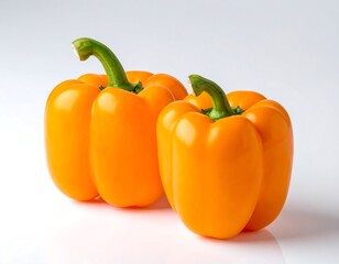 Two ripe, bright orange bell peppers with green stems, isolated on white