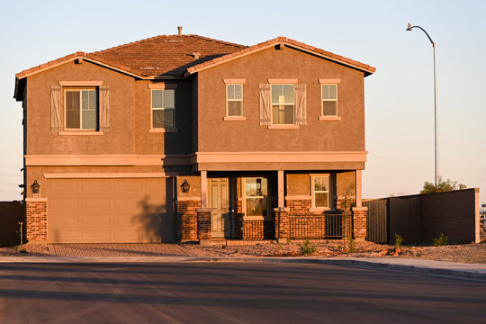 Newly constructed two-story single-family home with attached garage and stone-accent facade, representing unoccupied housing inventory in a developing suburban subdivision - Powered by Adobe
