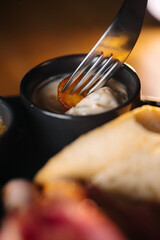 Macro shot of roasted potato on fork dipped in creamy sauce