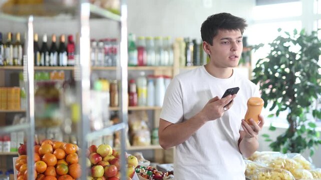 Male buyer checks suitability - scans QR code on jar of hot sauce label in a grocery store. High quality 4k footage
