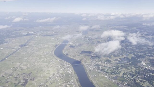View from airplane window flying over Japan &ndash; clouds and mountain landscape under clear blue sky
