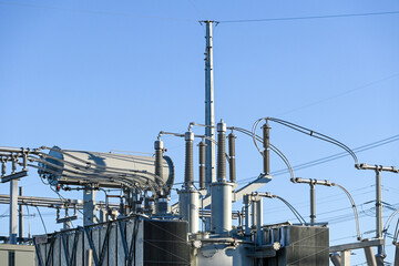 High-voltage electrical transformer system with insulators, bushings, and overhead conductors, representing industrial power infrastructure at a utility or battery facility