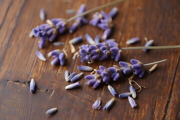 Lavender blossoms and petals scattered on a rustic wooden surface close up view