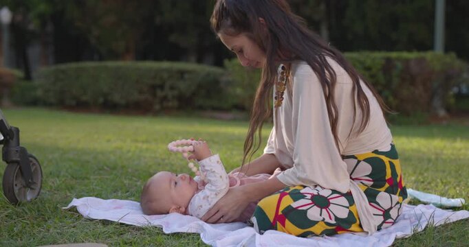 mother checking baby girls diaper while at park on summer day