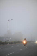 Cars drive through dense fog on a misty morning road