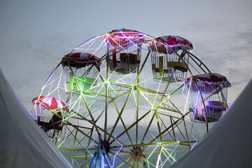 Bright Ferris wheel at dusk with colorful lights glowing