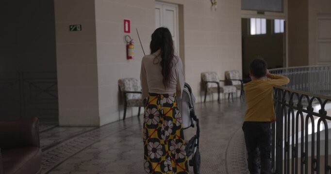 Mother walks with son and pushes stoller through museum on vaction