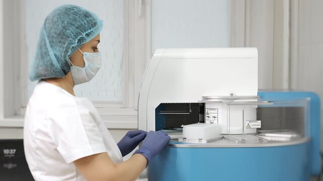 Medical laboratory technician operating automated nucleic acid extraction station for PCR testing in modern clinical lab environment.