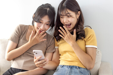 Excited Asian female students watching the smart phone