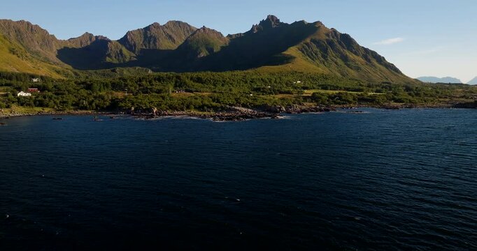 Uv&aelig;rshula coastal landscape with mountains and sea on sunny day, Stokmarknes, Norway. Aerial backward, copy space