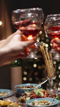 Vertical slow motion video cinematic camera moving above festive dinner table red wine glasses meeting in toast concept celebration togetherness thanksgiving christmas cozy home light