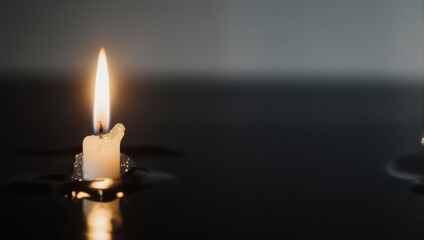 Fototapeta premium Single Lit Candle Illuminating a Dark and Reflective Surface.