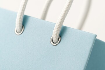 Light blue shopping bag macro diagonal focusing on handle knots on white