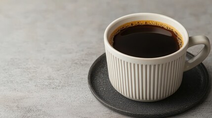 Close up of black coffee in a textured white ceramic mug resting on a dark speckled saucer