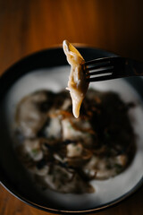Dumplings with sour cream in rustic ceramic bowl