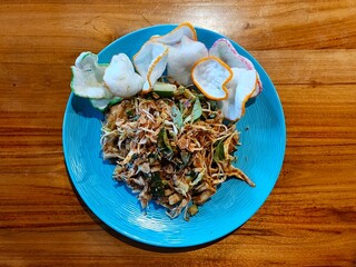 Karedok, an Indonesian salad with peanut sauce, served on a blue plate with crackers.