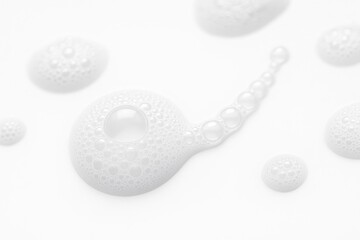 Separated foam clusters extreme macro diagonal focusing on a round cluster with crisp meniscus detail on white