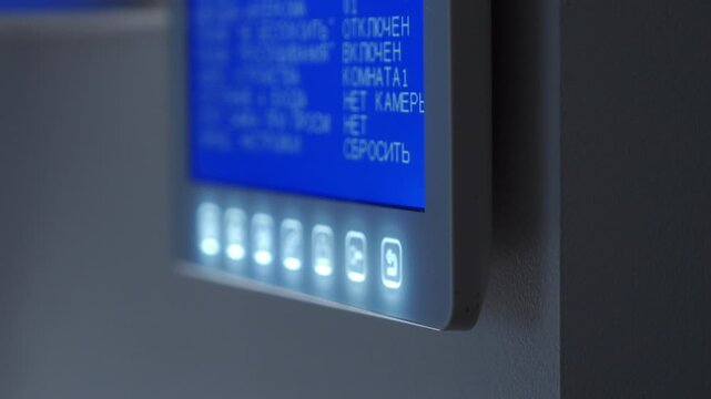An apartment intercom system rings, its screen and buttons glowing in the dark. The device chimes with a loud ding-dong sound.
