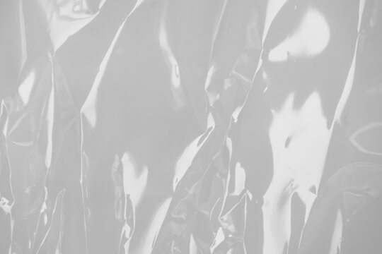 plastic transparent cellophane bag on white background. The texture looks blank and shiny. The plastic surface is wrinkly and tattered making abstract pattern