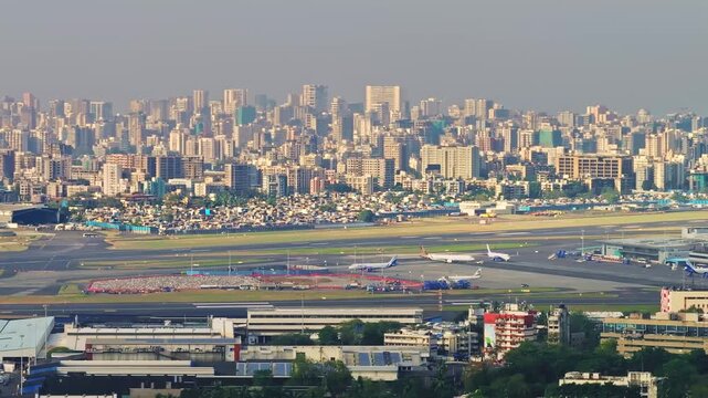 Cinematic 4K aerial drone shot with truck right slider movement showing Mumbai airport runway and dense city skyline on a bright clear day.