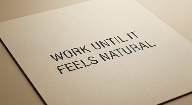 Inspirational quote card with the message 'Work until it feels natural' printed in bold black letters on a textured white background