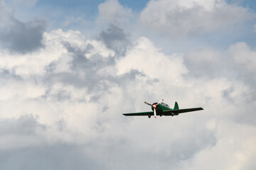 Vintage Green Propeller Plane Flying Against Dramatic Cloudscape
