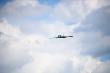 Light aircraft flying overhead against a clear sky with scattered clouds