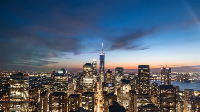 Panoramic view of a cityscape at dusk with skyscrapers and a waterfront area under a blue and orange sky.