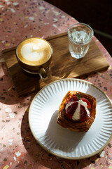 Hot coffee latte with latte art milk foam in cup mug and Homemade Fresh Strawberry and Cream Croissant on marble floor desk on top view. As breakfast In a coffee shop at the cafe,during business work.