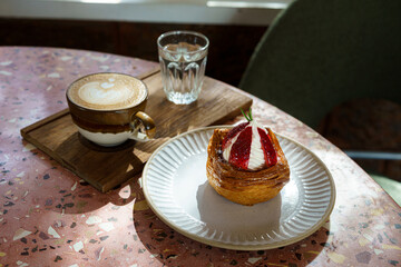 Hot coffee latte with latte art milk foam in cup mug and Homemade Fresh Strawberry and Cream Croissant on marble floor desk on top view. As breakfast In a coffee shop at the cafe,during business work.