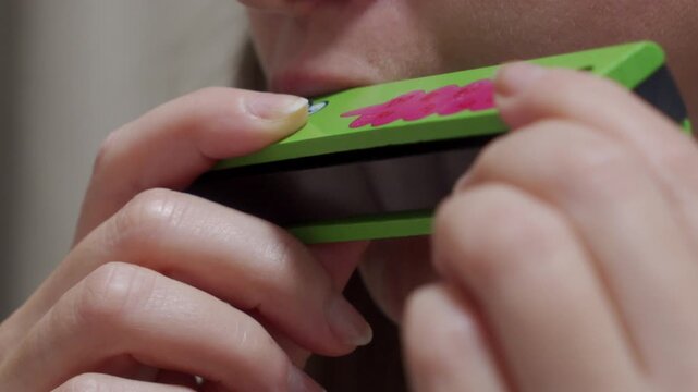 Distinct Note: Hands Hold Wooden Harmonica, Playing a Single Musical Tone.